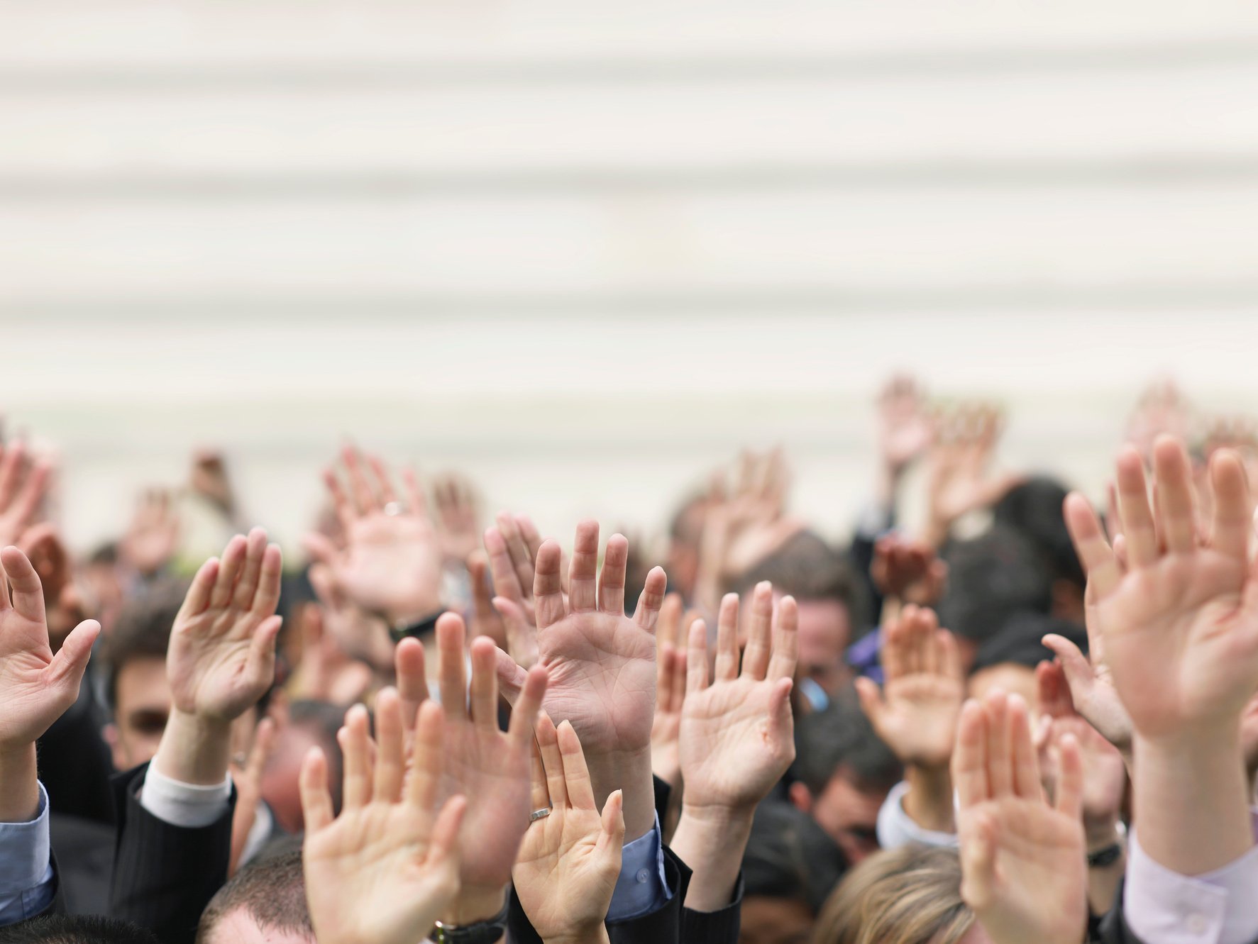 Crowd of people raising hands focus on hands